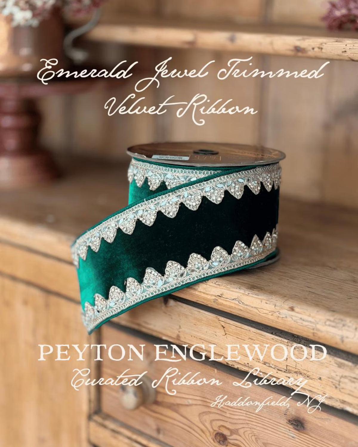 A spool of emerald green velvet ribbon with a scalloped border trimmed in sparkling silver rhinestones, displayed on a rustic wooden cabinet. Text overlays read 'Emerald Jewel Trimmed Velvet Ribbon' and 'PEYTON ENGLEWOOD Curated Ribbon Library'.