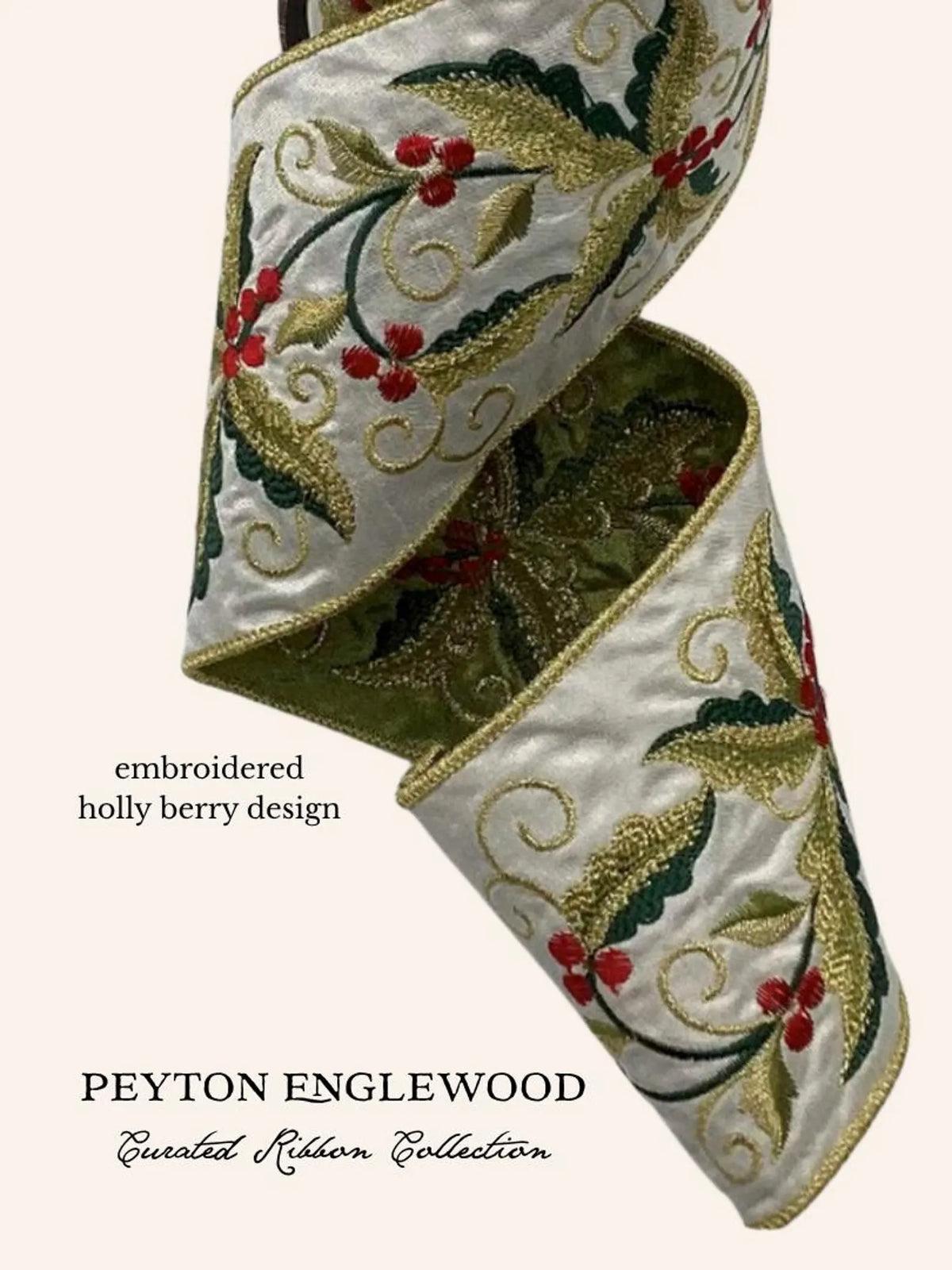 An embroidered ribbon with a holly and berry design, shown in a spiral fold on a light cream background. The ribbon features green leaves, red berries, and gold embroidery on a white satin base.